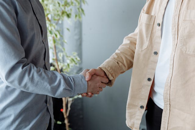 Two people shaking hands in an apartment building front entrance